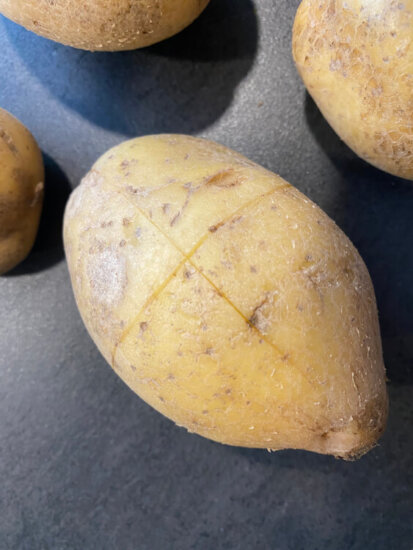 Kartoffel eingeschnitten um die Pellkartoffeln für Kartoffelpüree leichter zu schälen.