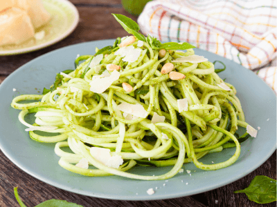 Zucchini Nudeln mit Pesto ist sowohl vegetarisch als auch Low Carb. Eine Schüssel mit frischen Zucchini-Nudeln, garniert mit Basilikumblättern