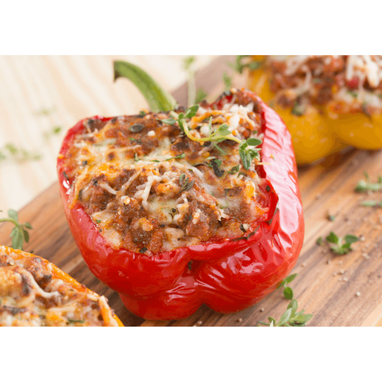 Gefüllte Paprika mit Hackfleisch als Low carb Gericht oder leckeres Abendessen angerichtet auf Holzbrett