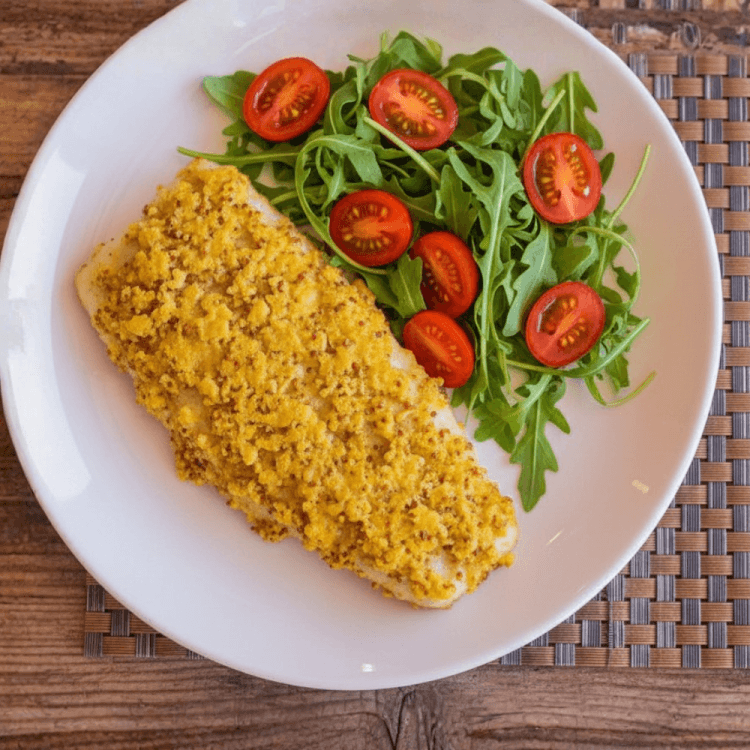Fischfilet in Senfkruste mit Rucola-Tomaten-Salat auf weißem Teller – Low carb Abendessen